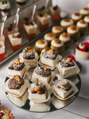 White and chocolate desserts with fruits and crem,  cupcakes on stand, modern sweet table at wedding or baby shower. Luxury catering concept. Delicious candy bar at wedding reception.