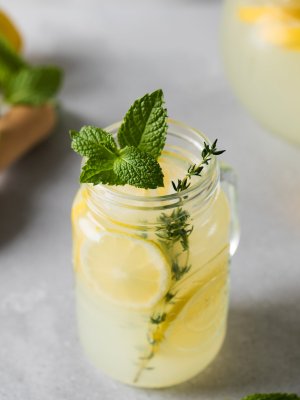 Homemade lemonade with fresh lemon slices and mint leaves in a glass. A summer refreshing drink with lemon.