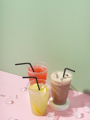 Colourful summer drinks with ice. Lemonades and milk shake on coloured background.