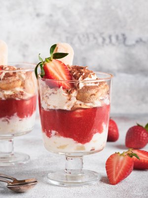 Strawberry tiramisu. Traditional Italian dessert tiramisu in glass with fresh strawberry and mint leaves on old gray concrete background table background. Copy space. Food background.